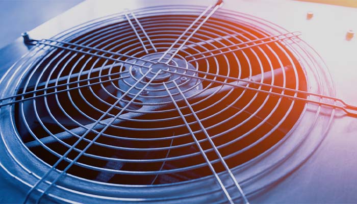 A professional HVAC technician examining a furnace and air conditioning system to identify unusual noises such as banging, rattling, hissing, or squealing.