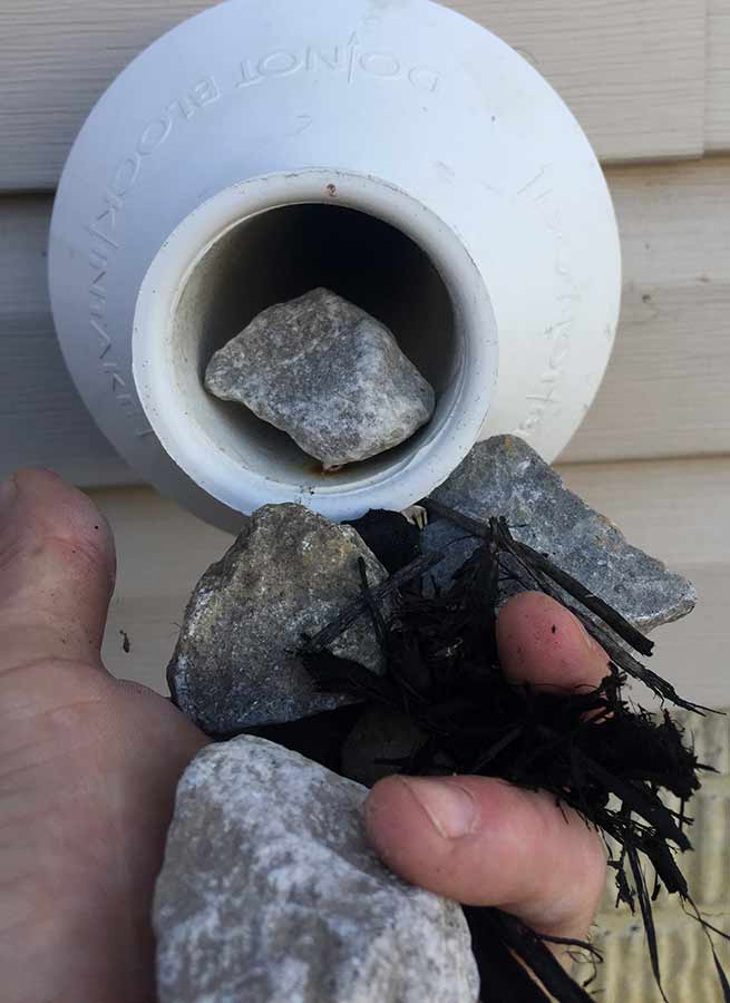 Rocks and mulch found blocking heating system piping during a Bryant Heating & Cooling service repair